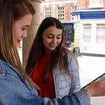 A level students using a tablet in a town