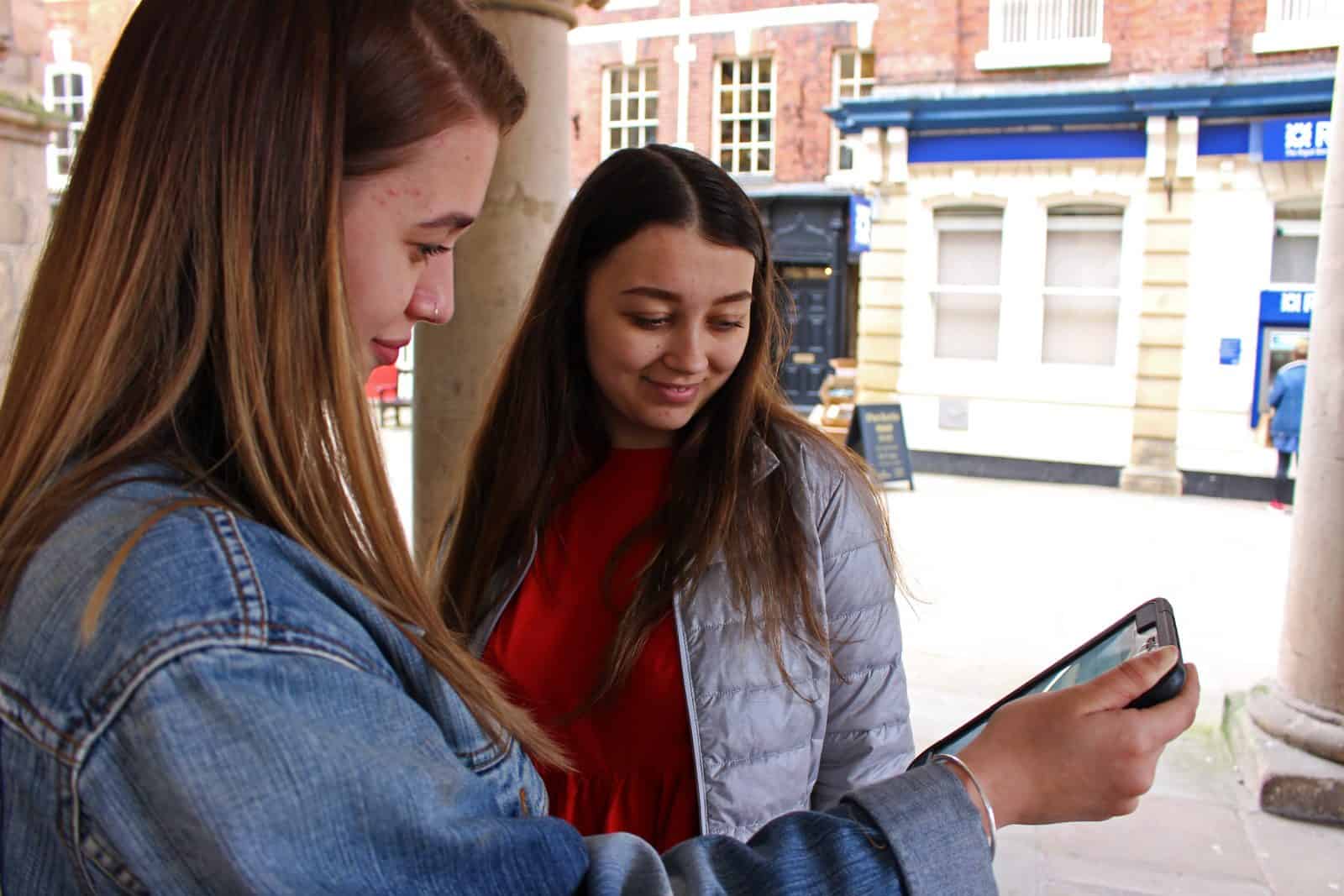 A level students using a tablet in a town