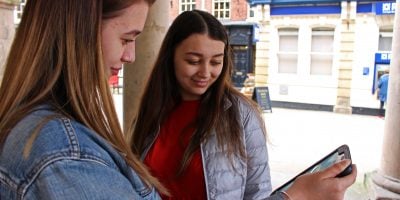 A level students using a tablet in a town
