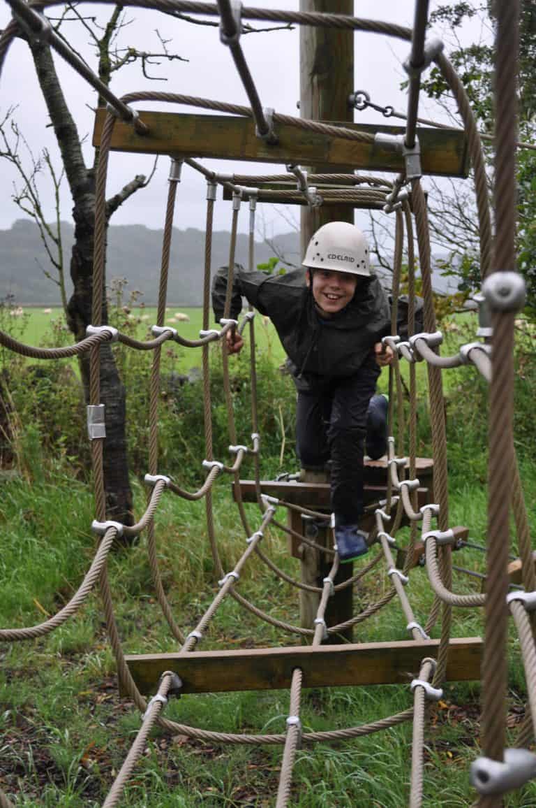 Child climbing through low ropes