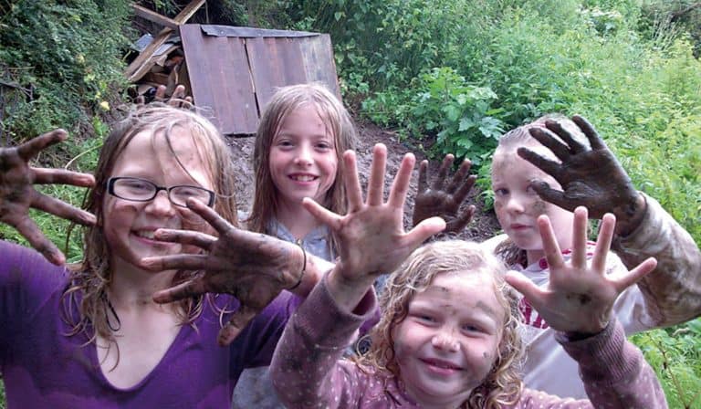 primary aged children showing their muddy hands