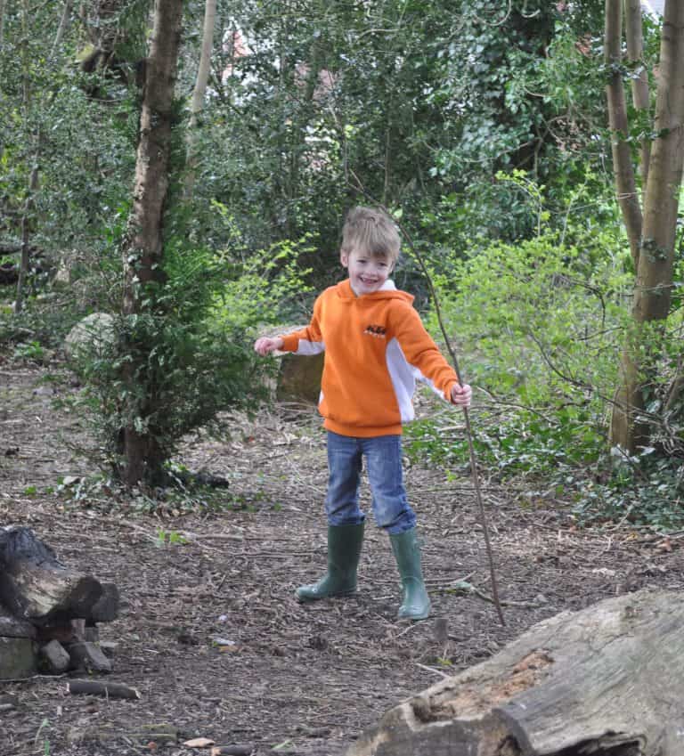 Young boy running and laughing around a forest