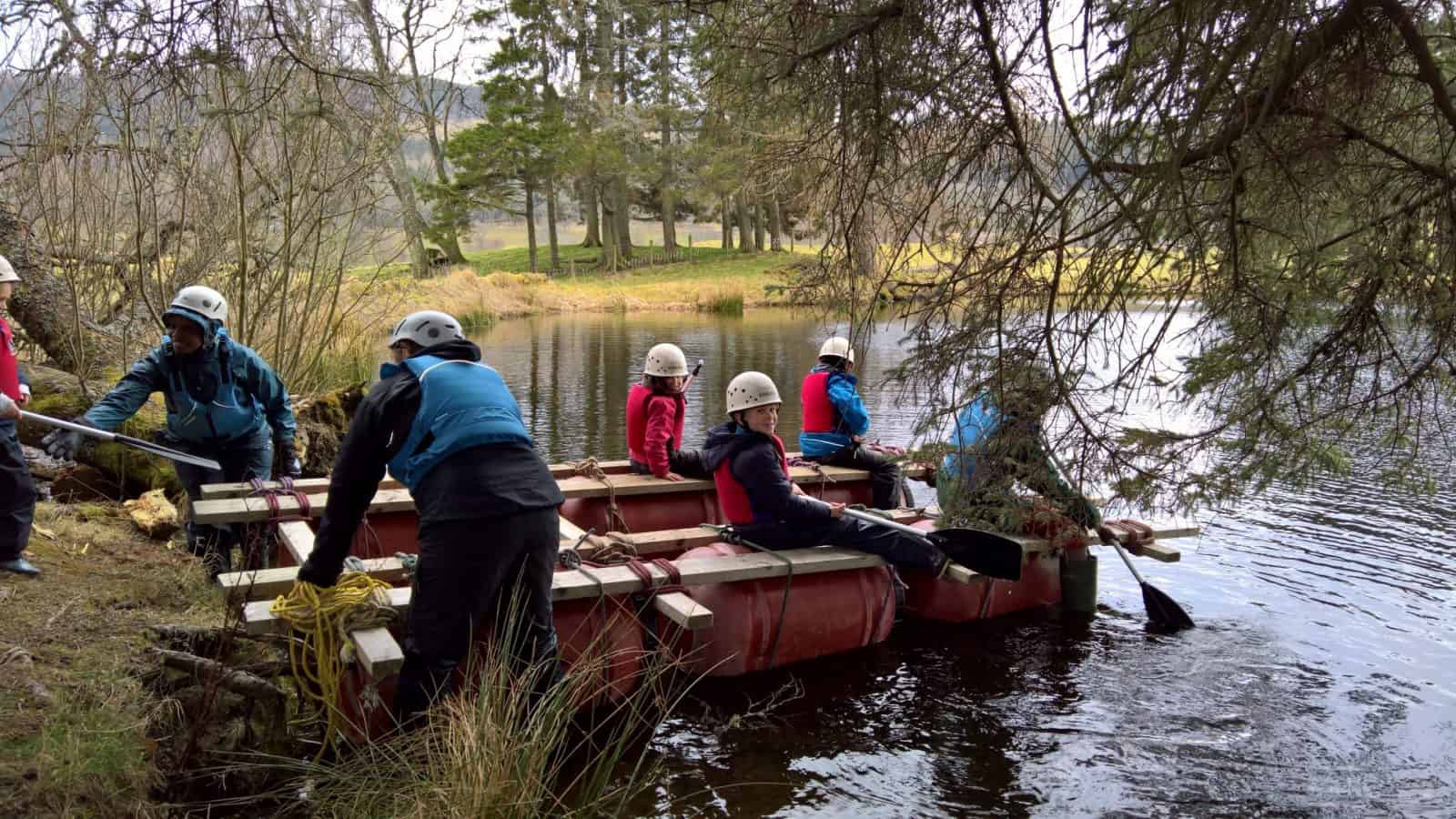 A group of people entering a lake on their raft