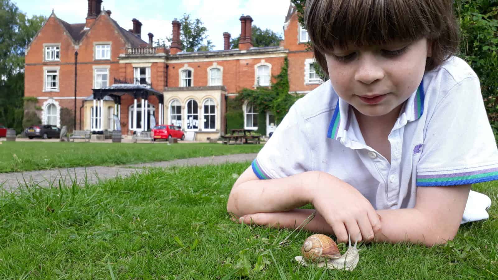 A boy looking at a snail in the FSC Juniper Hall grounds