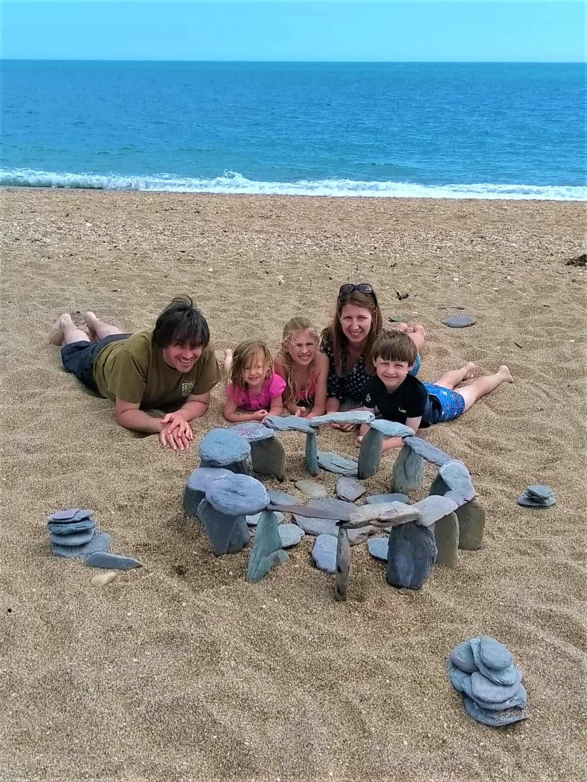 A family on the beach with their stone henge rock sculpture