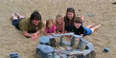 A family on the beach with their stone henge rock sculpture