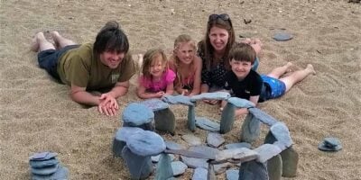 A family on the beach with their stone henge rock sculpture