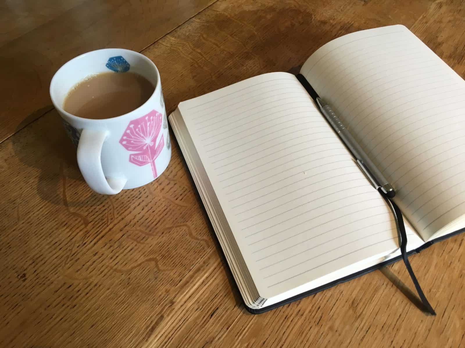 A cup of tea and a notebook and pen