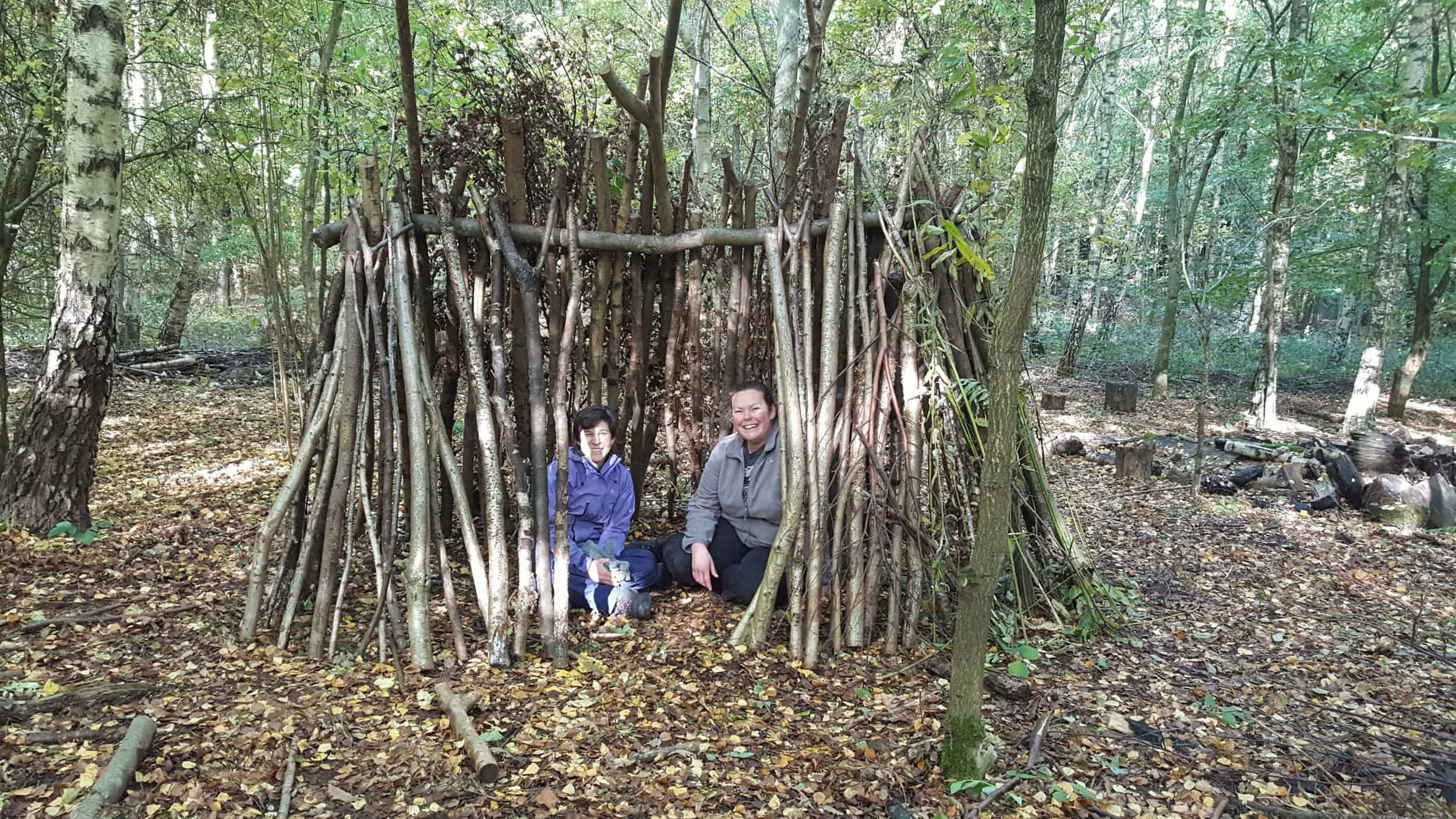 Two ladies sat in a wooden shelter in the woods