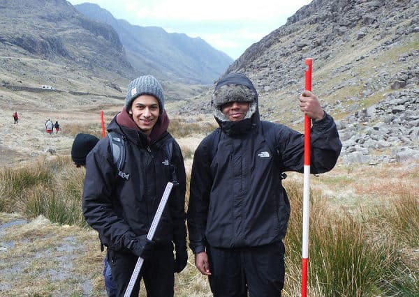 two students in mountains with ranging poles