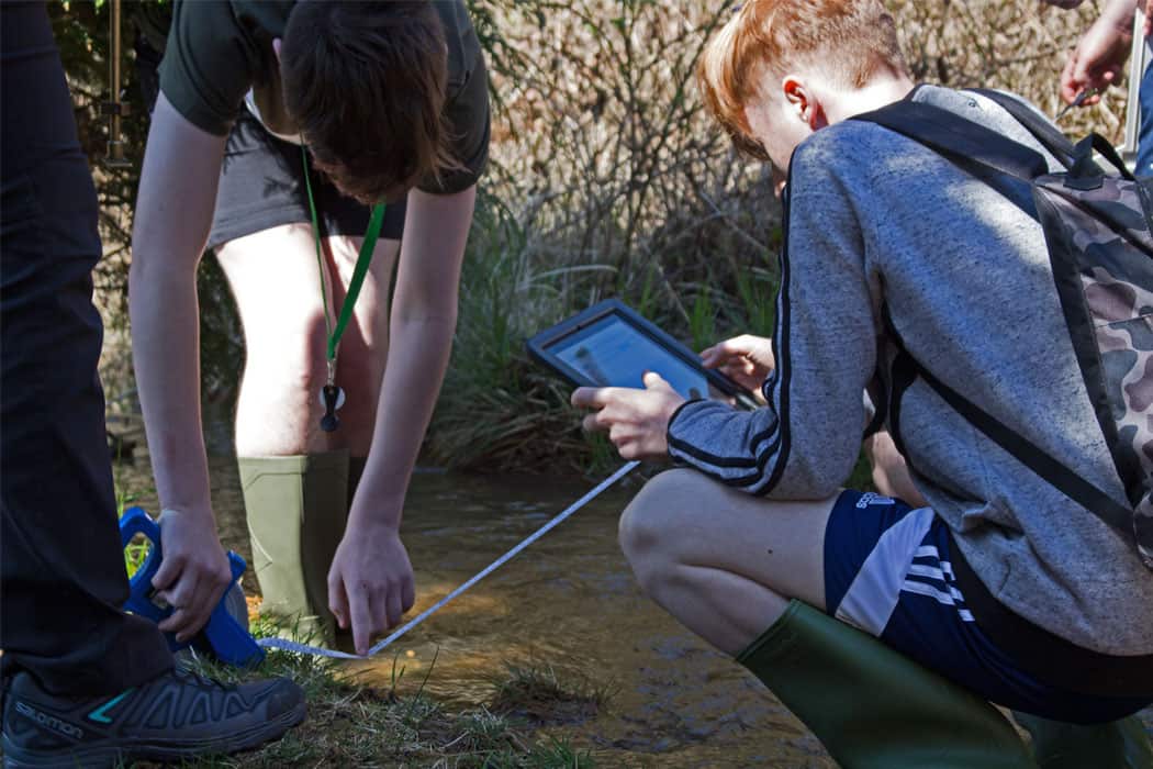 Boys measuring stream and using ipad