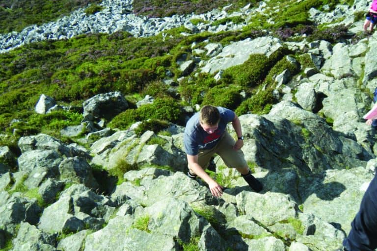 Geology student climbing up rocky upland in Shropshire