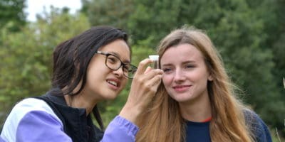 Two girls looking at insect in identification pot