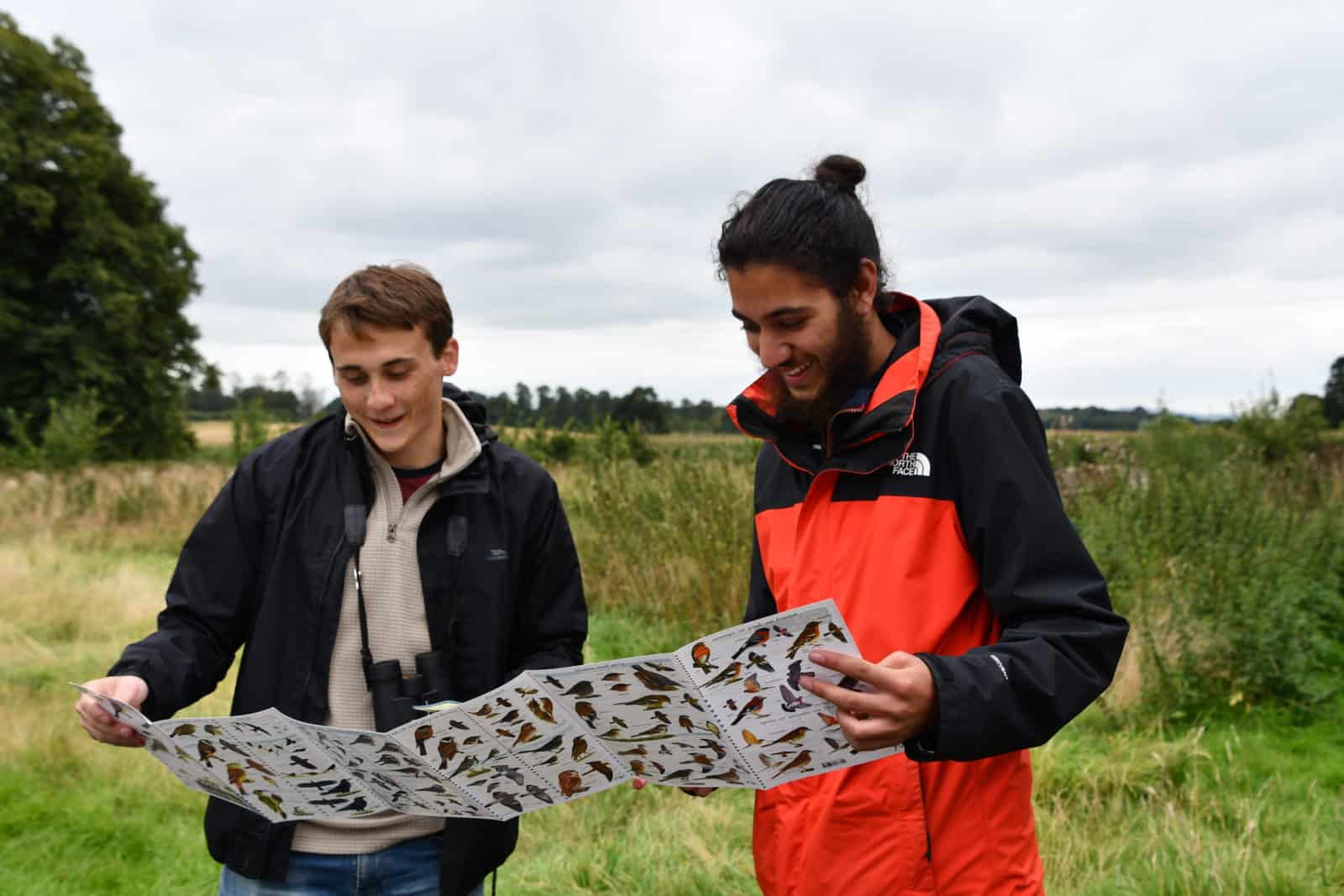 Two young people outdoors looking at wildlife ID guide