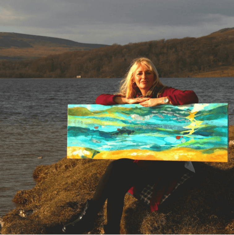 Linda holding a dramatic landscape painting