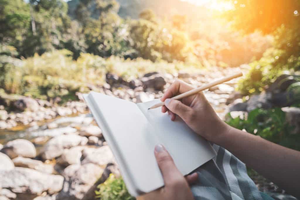 The begginng of writing. Pencil over a notebook in the beautiful outdoors.
