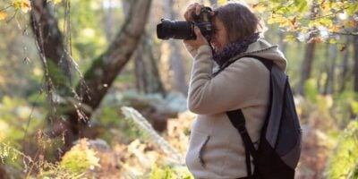 woman taking a photograph in woodland