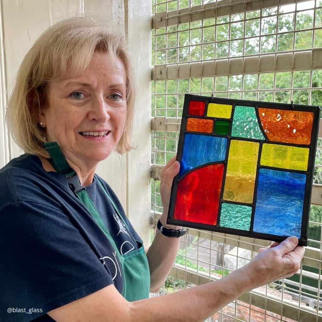 Lady with glass panel made on a Field Studies Council stained glass course.