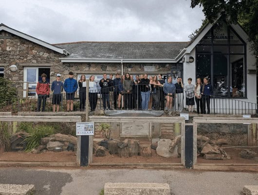 A photograph of a group of people stood in front of a building