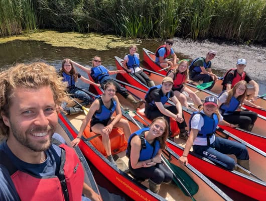 A group picture of people in red canoes