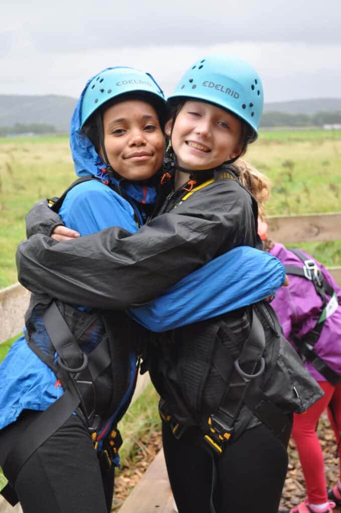 2 girls in safety gear celebrating after climbing the high ropes