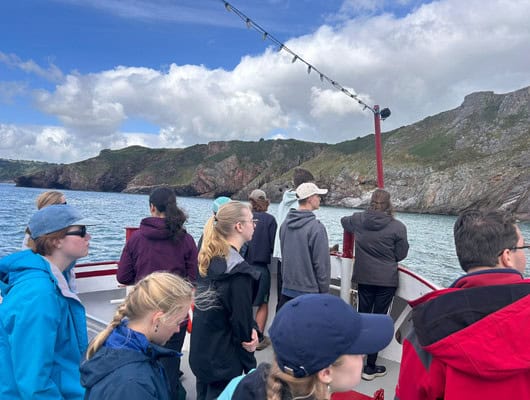 A photograph of a group of people on a boat looking at the hills