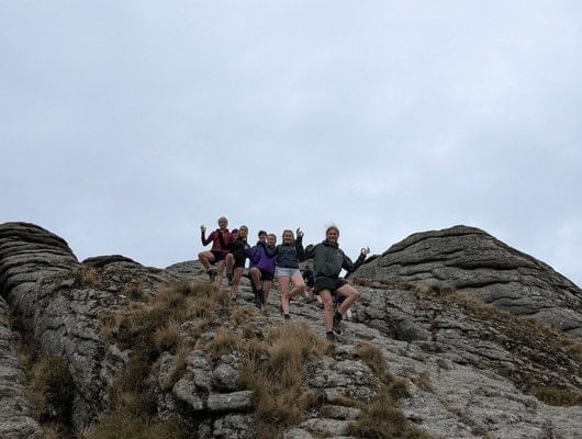 A group of people pulling a yoga pose on a rock