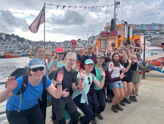A group of people waving to the camera
