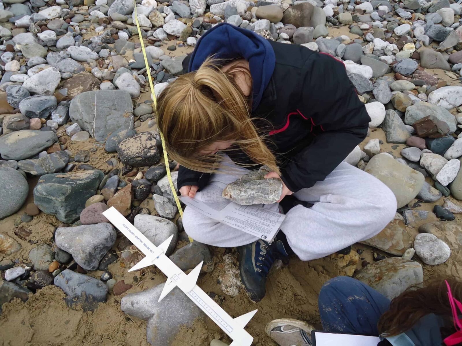 student measuring stones on beach for nea