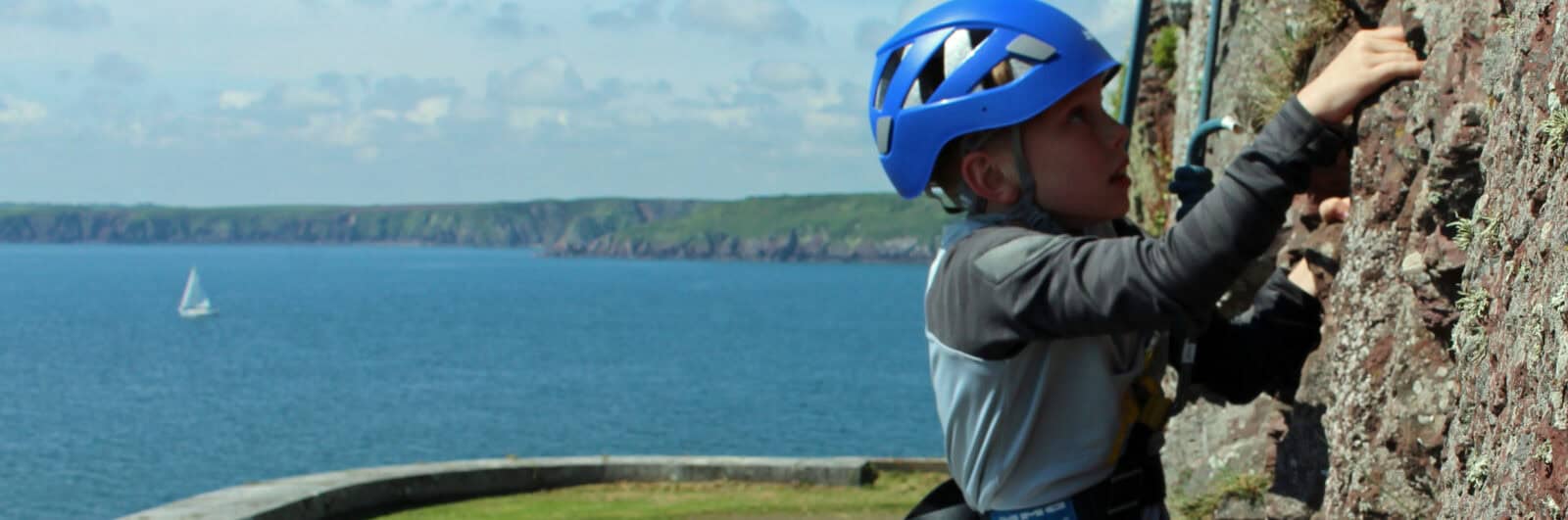 boy rock climbing with the sea in the background