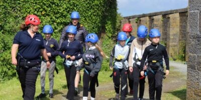 Tutor leads a primary group for adventurous activity at centre - climbing wall school group