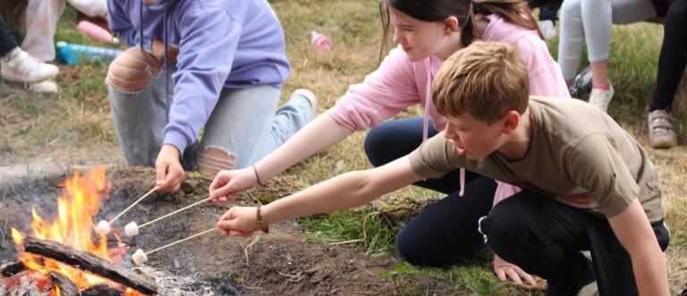 two children toasting marshmallows on a campfire
