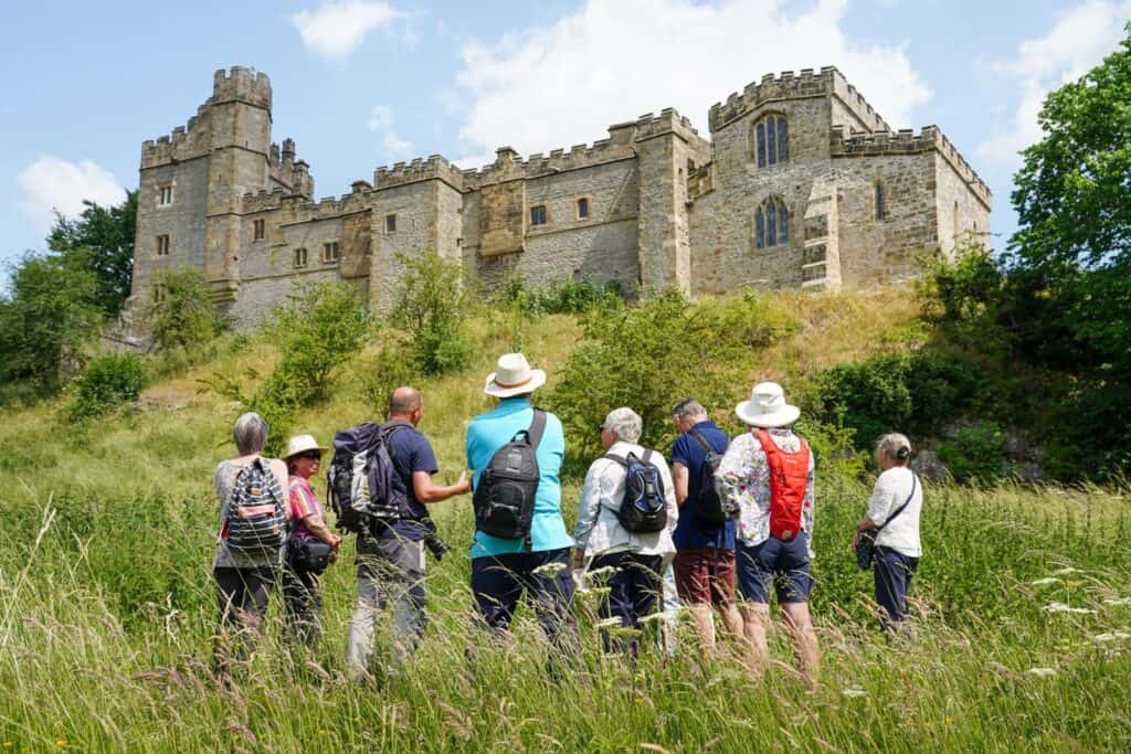 A group of adults on a training course with the manor house in the background.