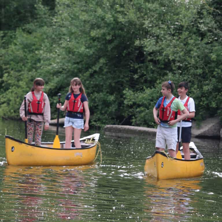 Group of children standing in canoes