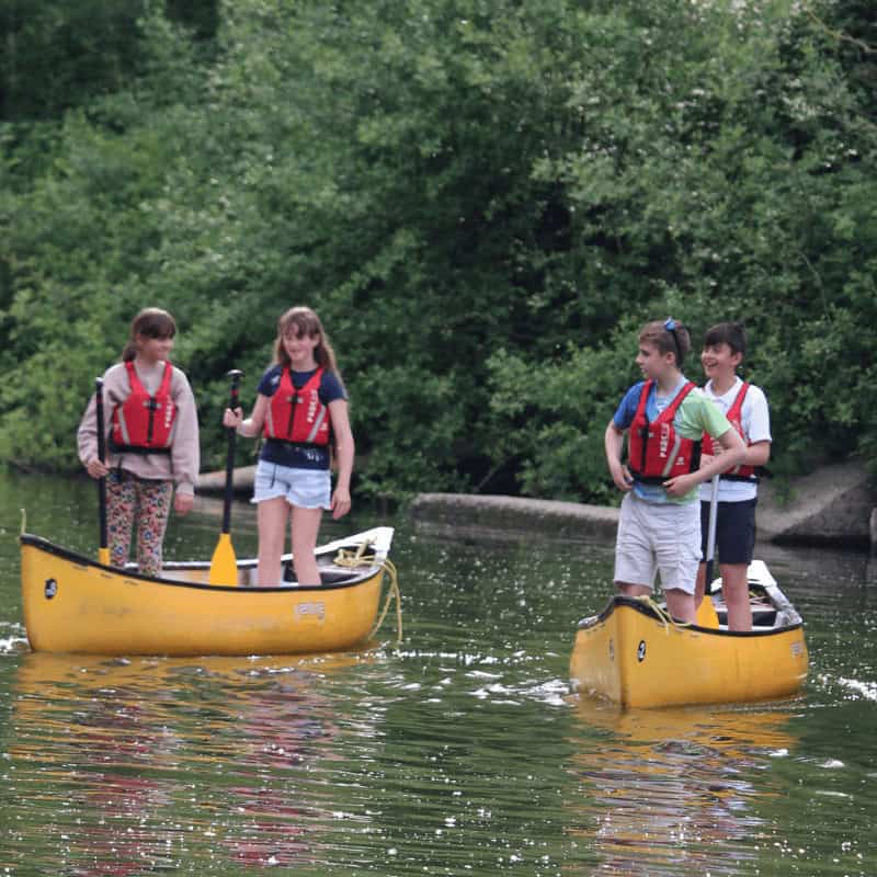 Group of children standing in canoes