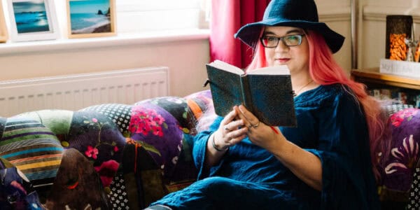 A photograph of a women in a witches hat, reading a book