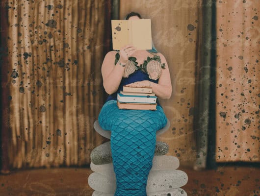 A picture of a mermaid reading a book