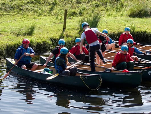 A photograph of a group of teens in canoes