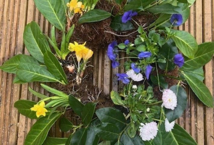 A picture of a wreath made from green leaves and spring flowers