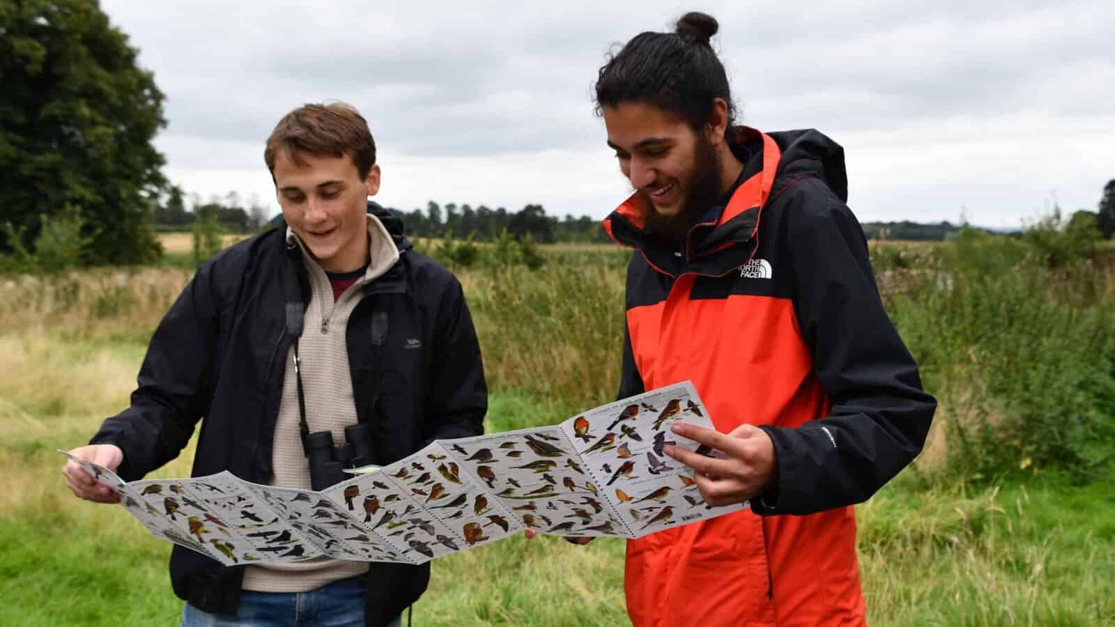 Two young people outdoors looking at wildlife ID guide