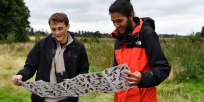 Two young people outdoors looking at wildlife ID guide on a day trips for schools