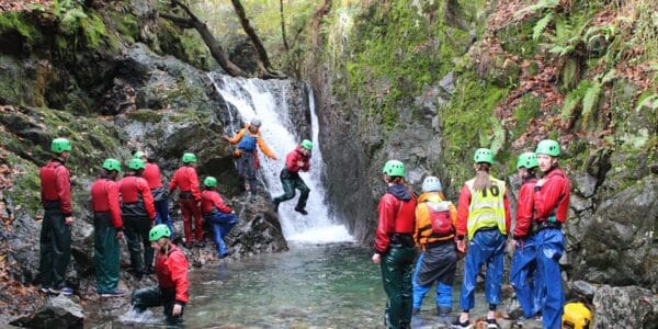 A photo of young people jumping into a waterfall - Adventure+ Camp