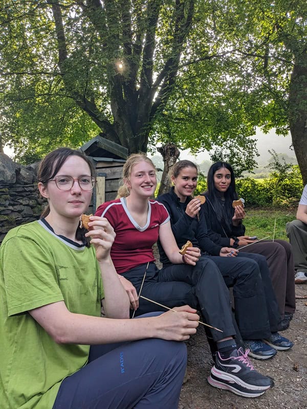 An image of young people sat on a bench together - Adventure+ Camp