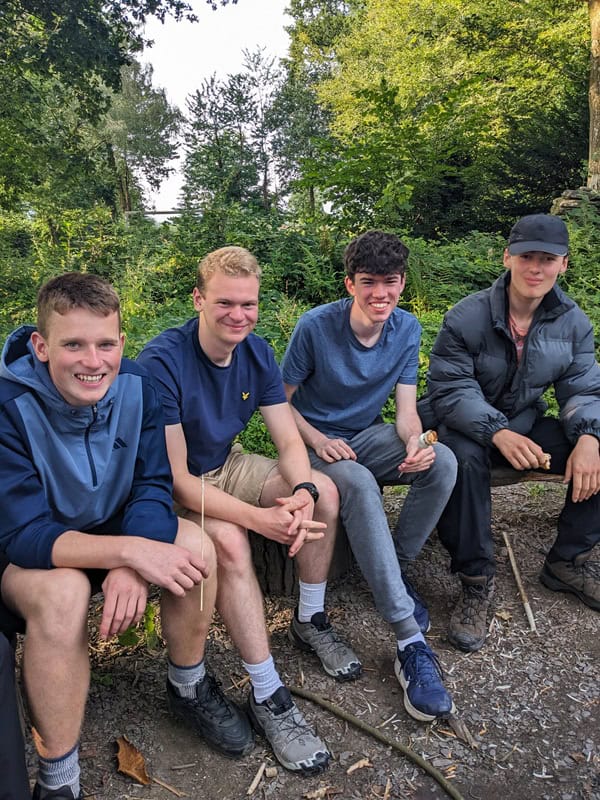 An image of young people sat on a bench together - Adventure+ Camp